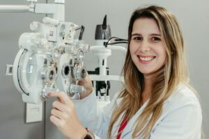 Female optician in white coat smiling while using phoropter. Perfect for healthcare imagery.