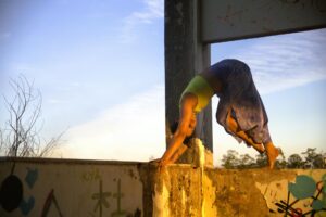 A woman gracefully performs a handstand on a wall with sunset in the background.