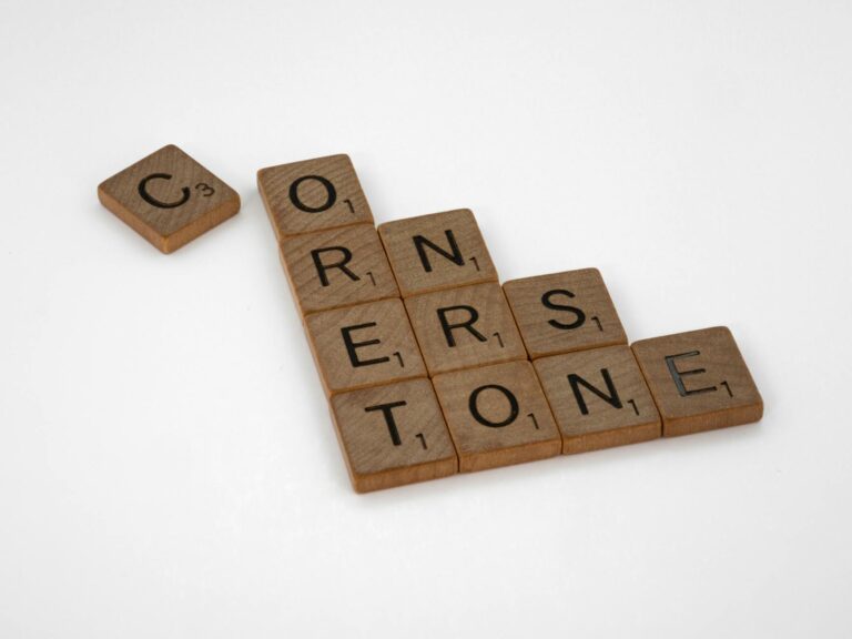 Close-up of Scrabble tiles spelling 'CORNERSTONE' on a white background.