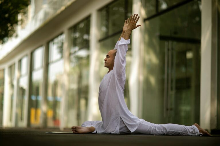 Side profile of a man performing yoga outdoors, stretching in a white outfit, showcasing relaxation and mindfulness.
