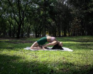 Woman performing a yoga pose on a sunny day in a lush green park in Ciudad de México.