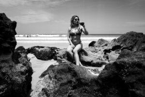 Black and white photo of a woman sunbathing among rocks on a beach in Natal, Brazil.