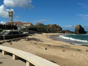 Sunny beach view of Praia de Santa Cruz with a scenic lighthouse and ocean waves.
