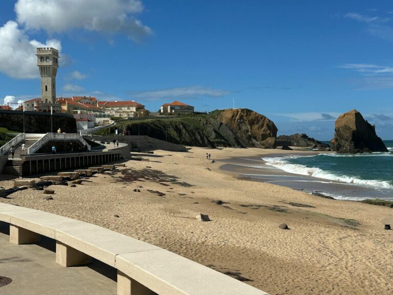 Sunny beach view of Praia de Santa Cruz with a scenic lighthouse and ocean waves.