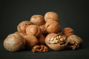 Close-up of whole and cracked walnuts on a dark background highlighting texture and detail.