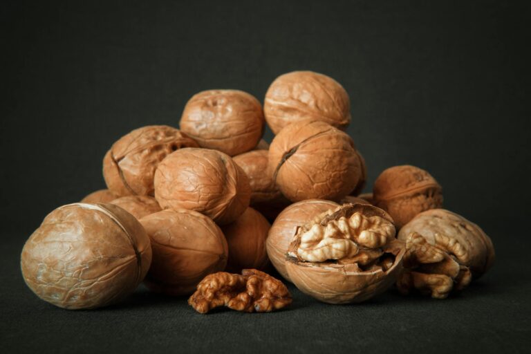 Close-up of whole and cracked walnuts on a dark background highlighting texture and detail.