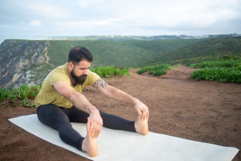 Bearded man stretching on a yoga mat amidst Portugal's scenic landscape, promoting outdoor fitness