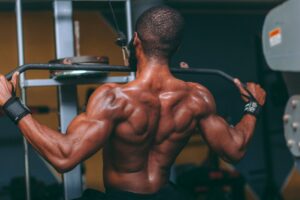 A muscular man performing lat pulldowns in a gym, showcasing strength and fitness.