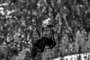 A person enjoys paragliding over a winter landscape, capturing the thrill of flight.