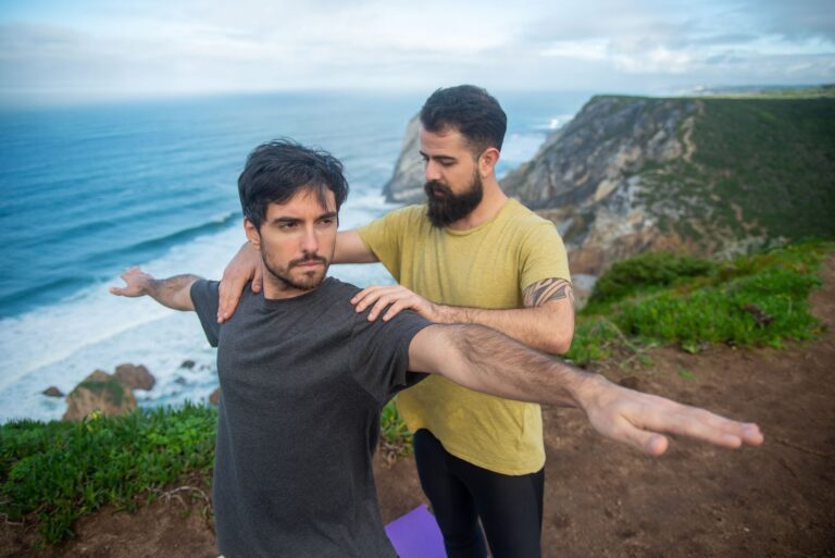 Two men practicing yoga on a stunning cliffside overlooking the ocean in Portugal.