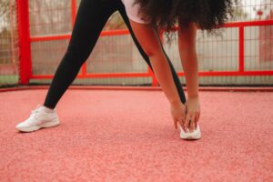 Close-up of a woman stretching on a vibrant red sports field, focusing on fitness.