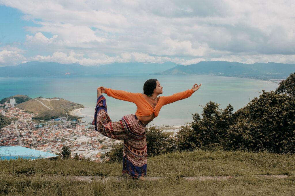 Woman in yoga pose overlooking the beautiful landscape of Paraty, Brazil, with sea and mountains.