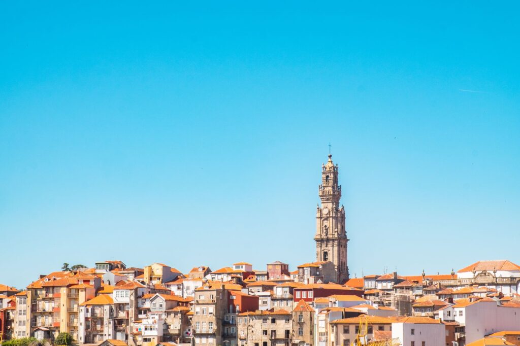 Baroque Clérigos Tower standing tall in Porto, Portugal cityscape under a vivid blue sky.